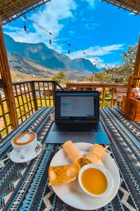 A MacBook showing the Review Enhanced Prompt modal on a bamboo terrace in Sa Pa, Vietnam, mountains behind it